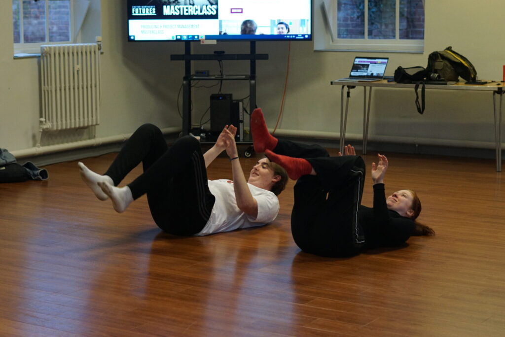 two drama facilitators lie on their backs on the floor