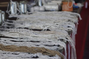 A pile of finished macrame holders sit along the edge of the stage